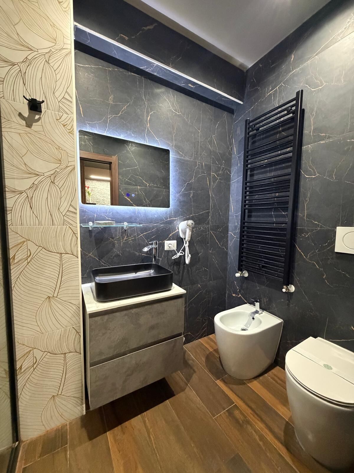 Et moderne badeværelse med marmor bagvæg, et indbygget håndvaskarrangement, et toilet og en bidet.