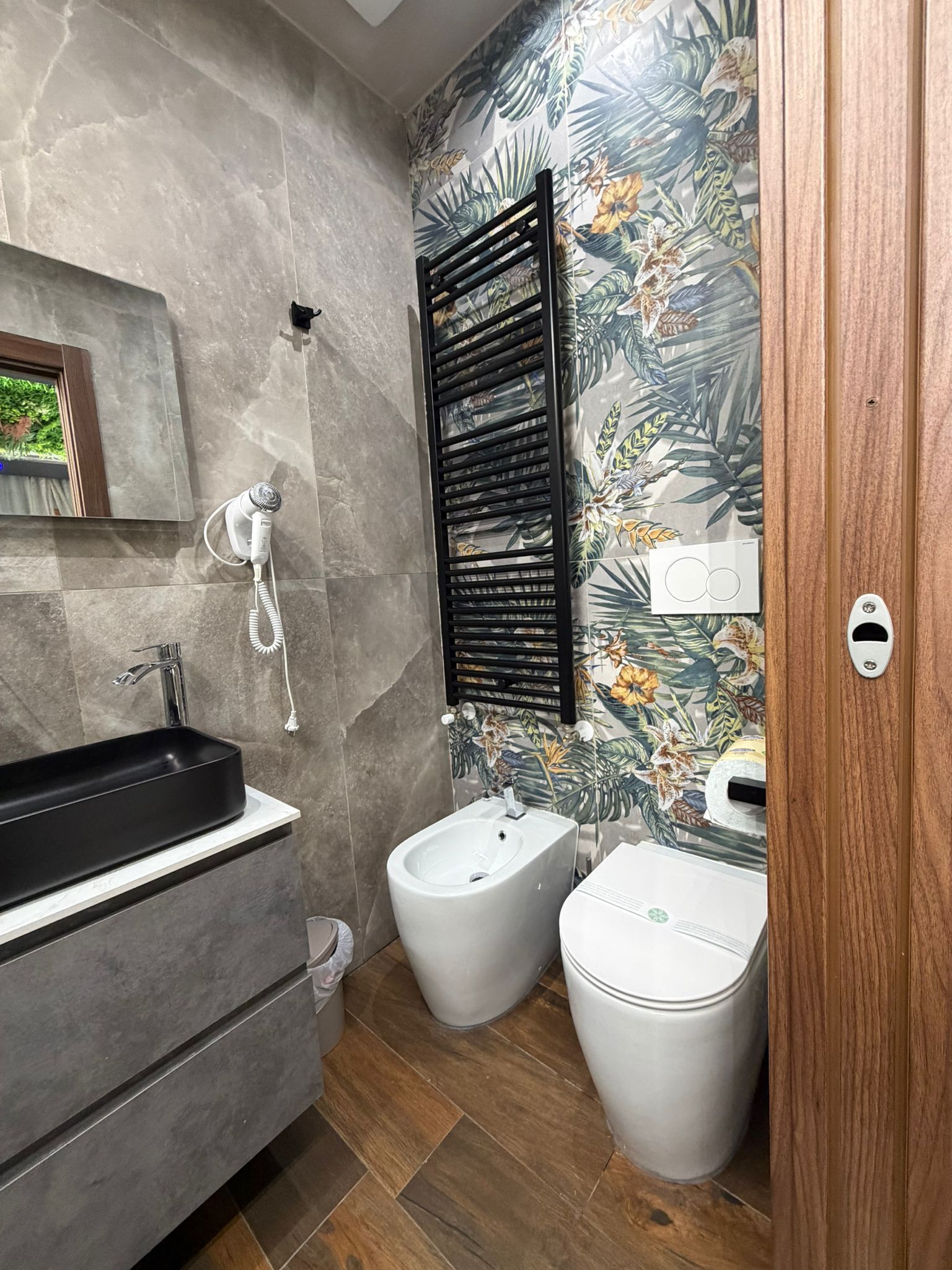 A modern bathroom with a black sink, bidet, and a mirror.