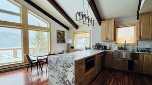 Una cocina moderna con pisos de madera, ventanas amplias y una isla de mármol.