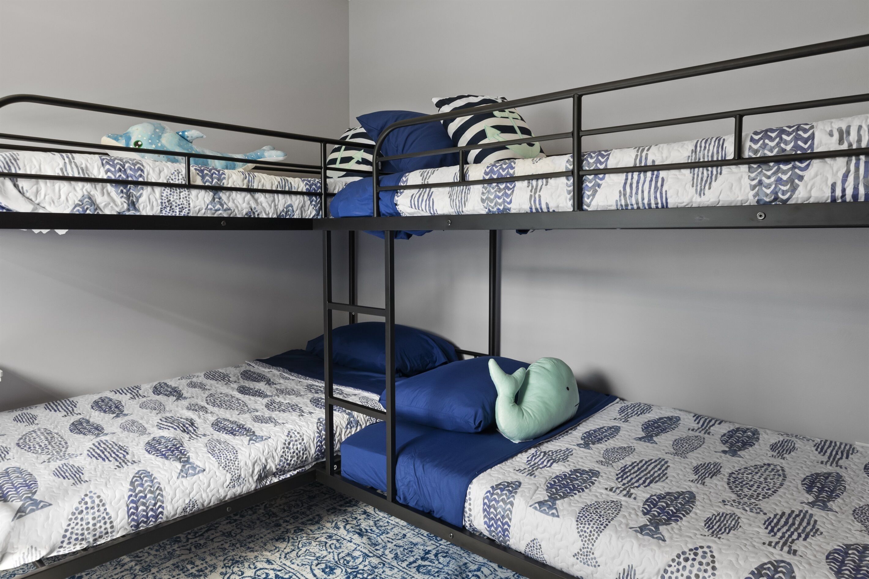 Een slaapkamer met een stapelbed, beddengoed met een patroon en een ladder.