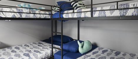 Een slaapkamer met een stapelbed, beddengoed met een patroon en een ladder.