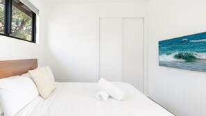 Ein Schlafzimmer mit einem Bett, einer Tür und einem Wandbild einer Welle.