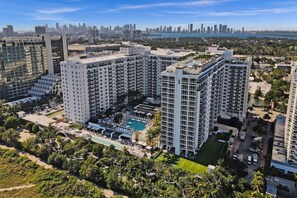 A high-rise hotel with multiple floors, a rooftop pool, and a view of a city skyline. - 1 Hotel South Beach Designer 2BR with Ocean Views (Miami Beach)