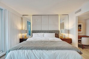 Een moderne hotelkamer met een groot bed, nachtlampjes, een bureau en een stoel.