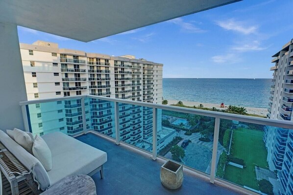 A balcony with a view of the ocean and a pool area.