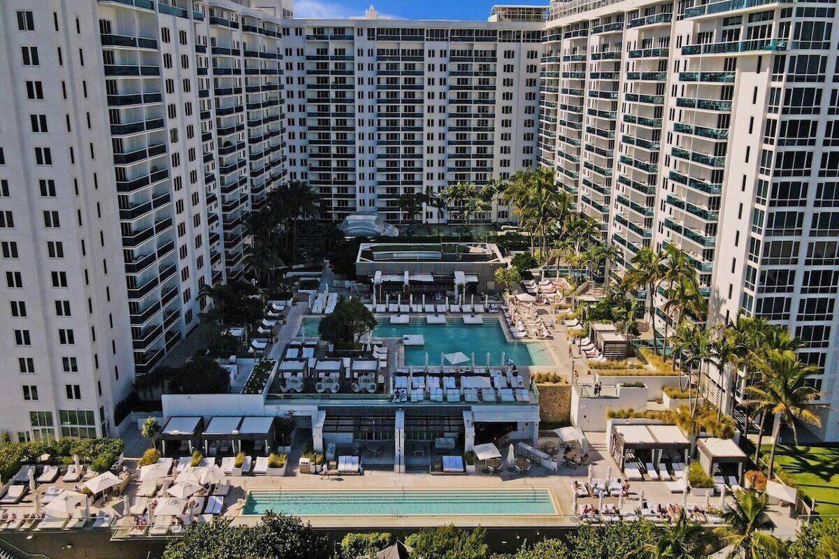 Un hôtel de grande hauteur doté de nombreux balcons, d’une piscine centrale et de chaises longues.