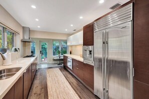 Una cocina moderna con electrodomésticos de acero inoxidable, armarios de madera y una isla central.