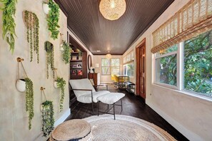 A room with a white chair, a woven rug, and hanging plants.