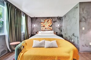 Une chambre d’hôtel moderne avec un grand lit, un tableau au mur et une vue sur l’extérieur.
