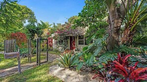 A garden with a mailbox, a wooden fence, and various plants. - Luxury Morningside Bungalow Steps to the Park (Miami)
