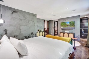 Un dormitorio moderno con una cama grande, televisión y vistas al exterior.