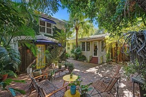 A courtyard with outdoor seating, potted plants, and a building with a yellow door.