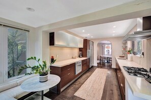 A modern kitchen with a central island, built-in appliances, and a dining area with a round table.