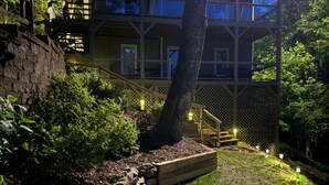 Un espace extérieur à plusieurs niveaux, agrémenté d’escaliers en pierre, de bancs en bois et d’un arbre.