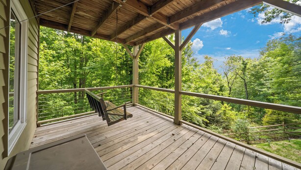 Une terrasse en bois avec une rambarde, un banc et une vue sur une forêt.