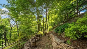Une zone boisée, délimitée par un mur de pierre et une clôture en bois.