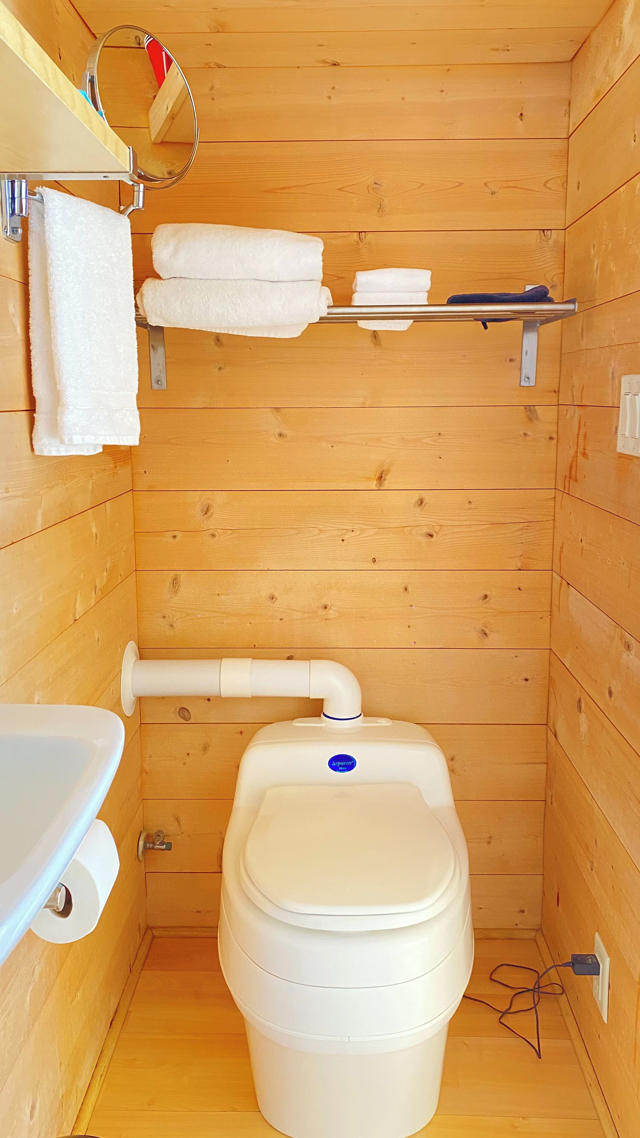 Une petite salle de bain en bois comprenant des toilettes, un lavabo et un porte-serviettes.