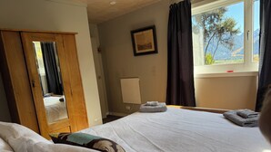 Ein Hotelzimmer mit Bett, Spiegel, Fenster und Bergblick sowie einer Tür.