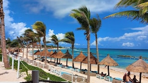 A beach resort with thatched umbrellas, lounge chairs, and a pool area. - Tulum Country Home (Akumal)