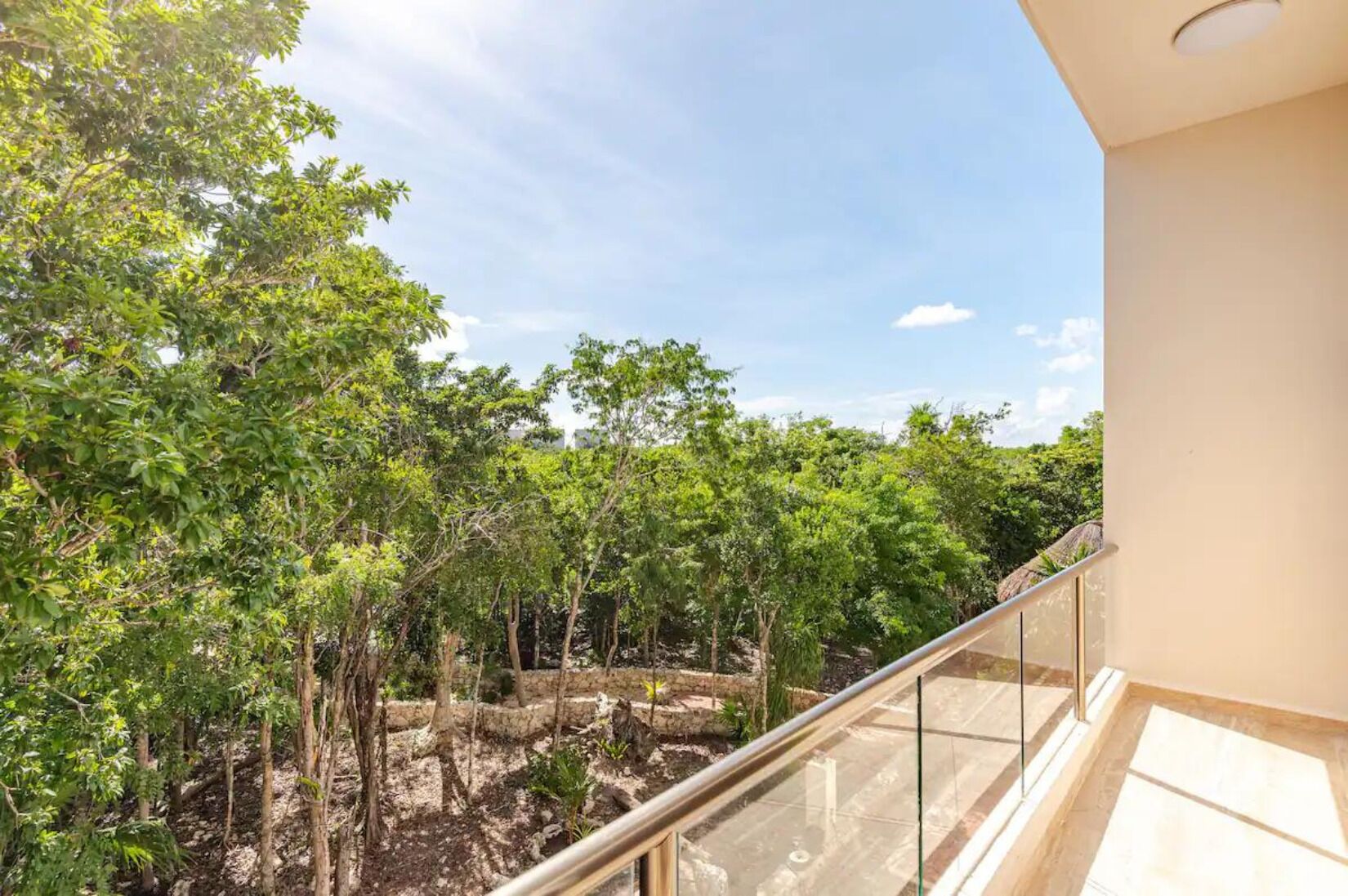 A balcony with a view of a lush garden and trees.