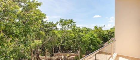 A balcony with a view of a lush garden and trees.