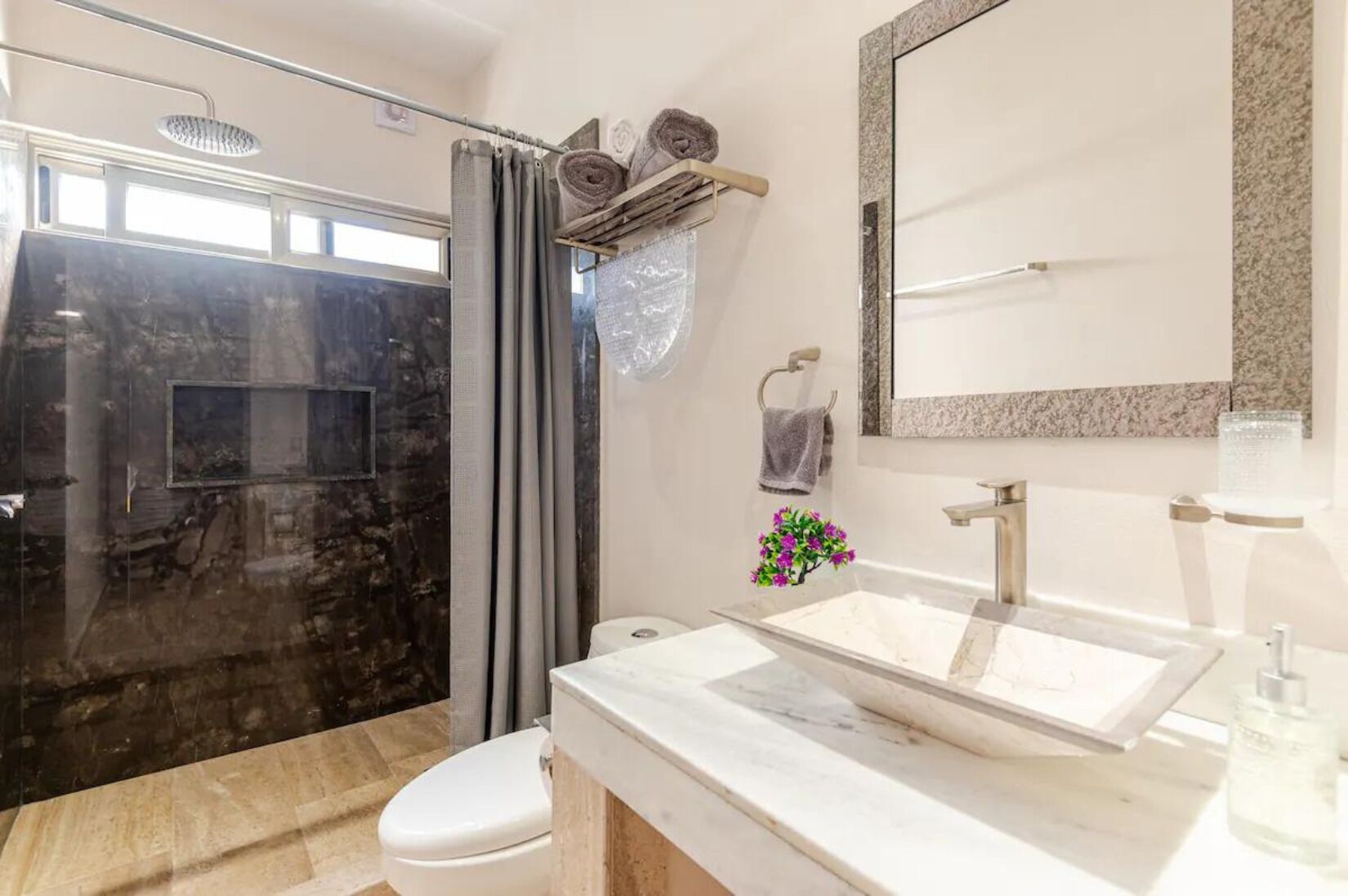 Une salle de bain moderne avec une douche à parois de verre, un grand miroir et un lavabo en marbre.