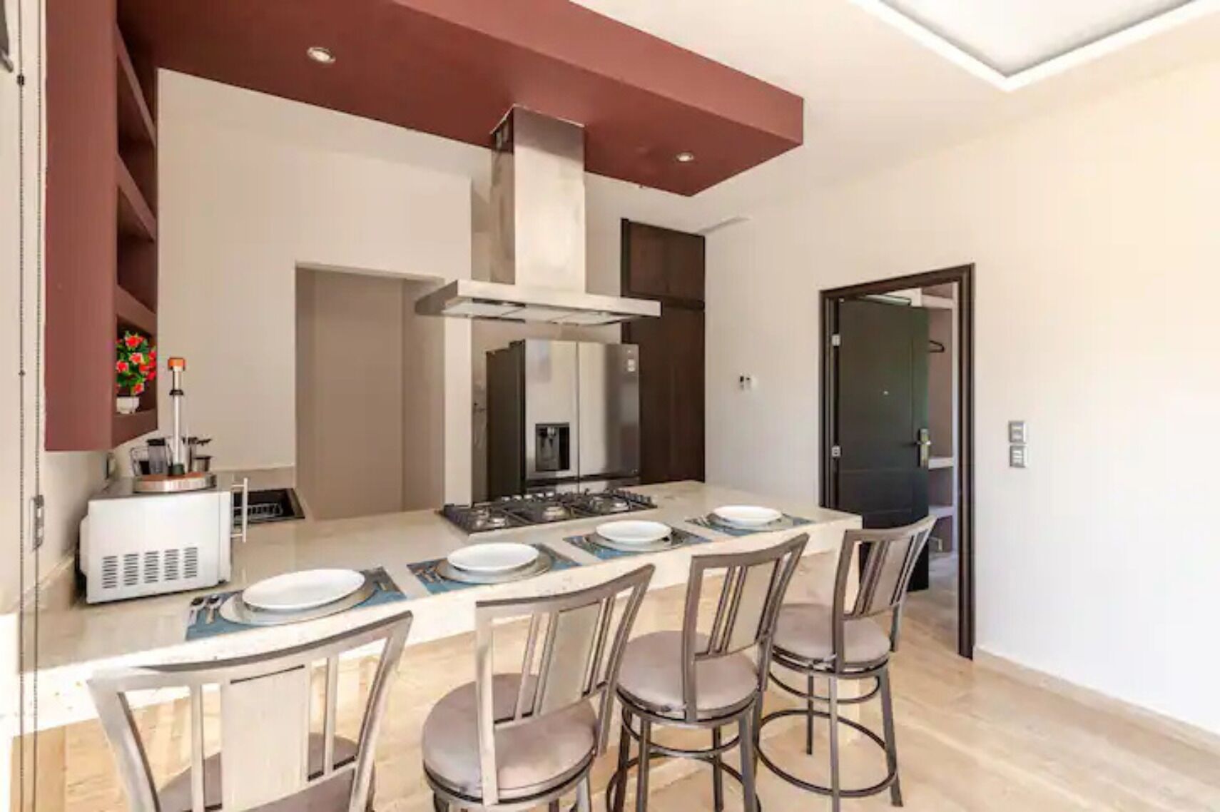 A modern kitchen with a central island, stainless steel appliances, and a large window.