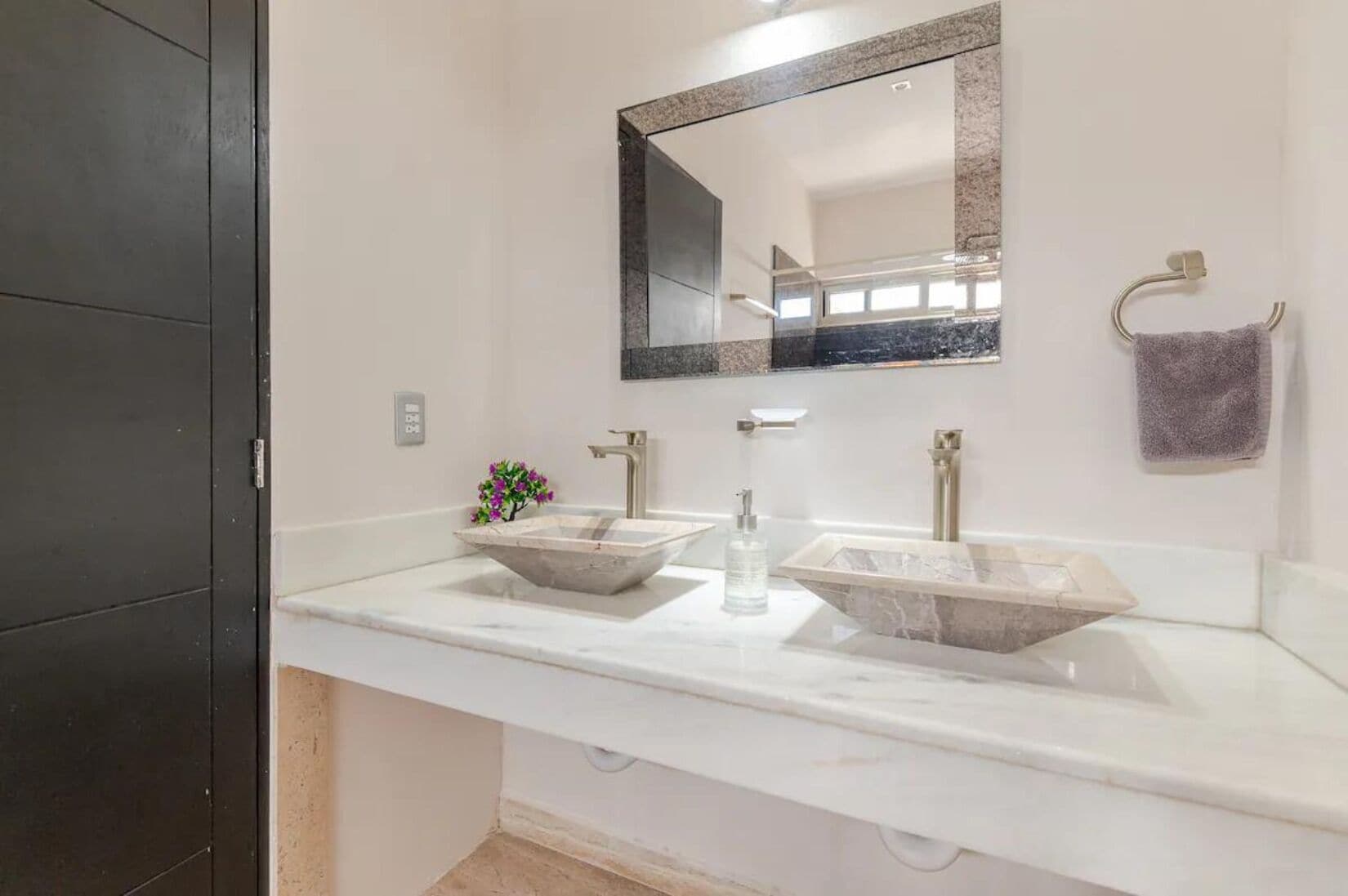 A bathroom with two large, rectangular vessel sinks, a mirror, and a towel rack.