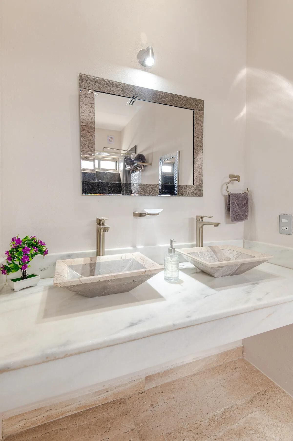 A bathroom with two vessel sinks, a large mirror, and a potted plant.