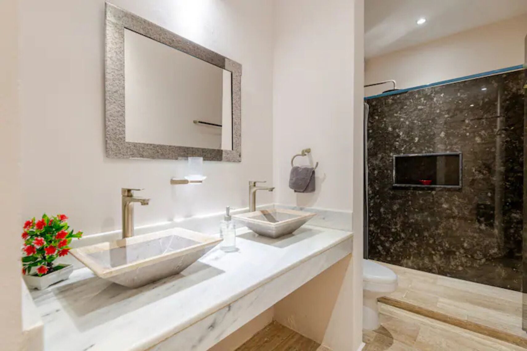 Une salle de bain moderne avec deux lavabos, un grand miroir et un espace douche.