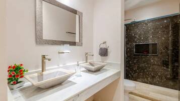 Un baño moderno con dos lavamanos, un espejo grande y una zona de ducha.