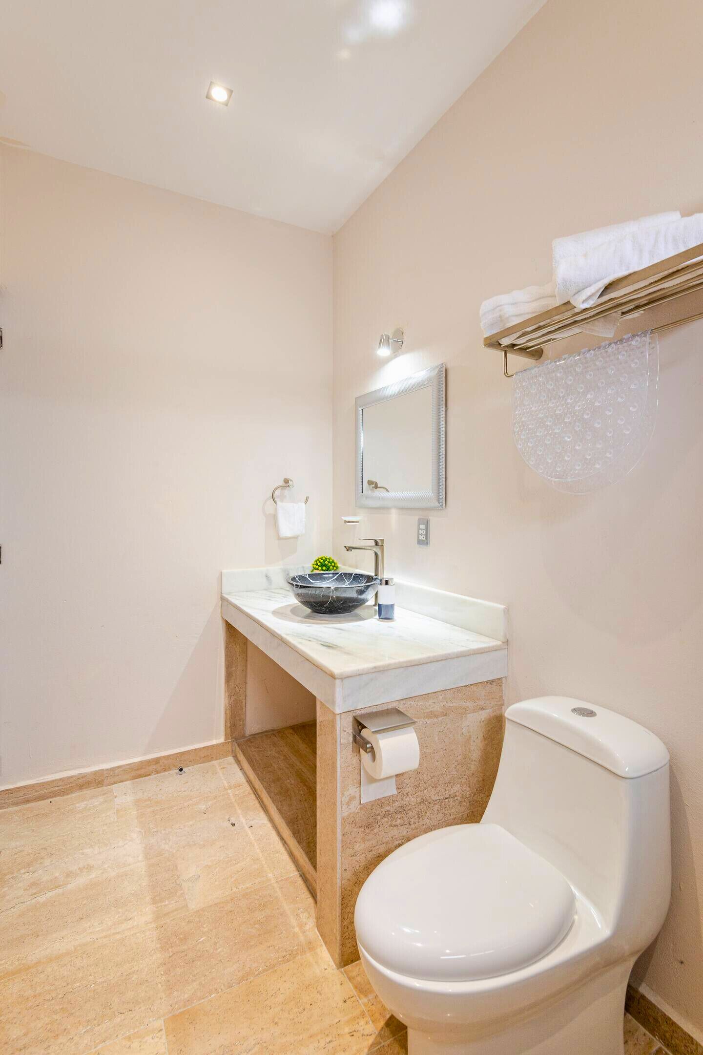 Een badkamer met een marmeren wastafel, toilet en handdoekrek.