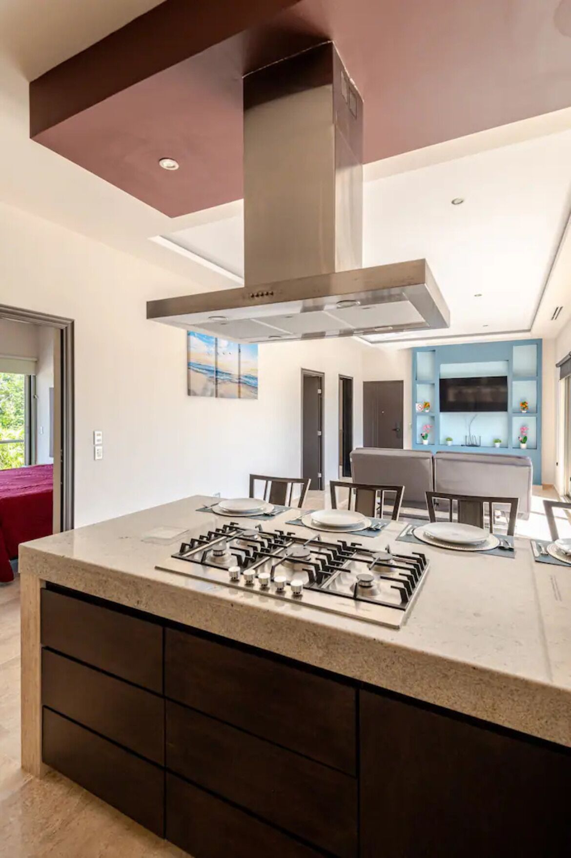 A modern kitchen with a central island, built-in cabinets, and a stainless steel range hood.