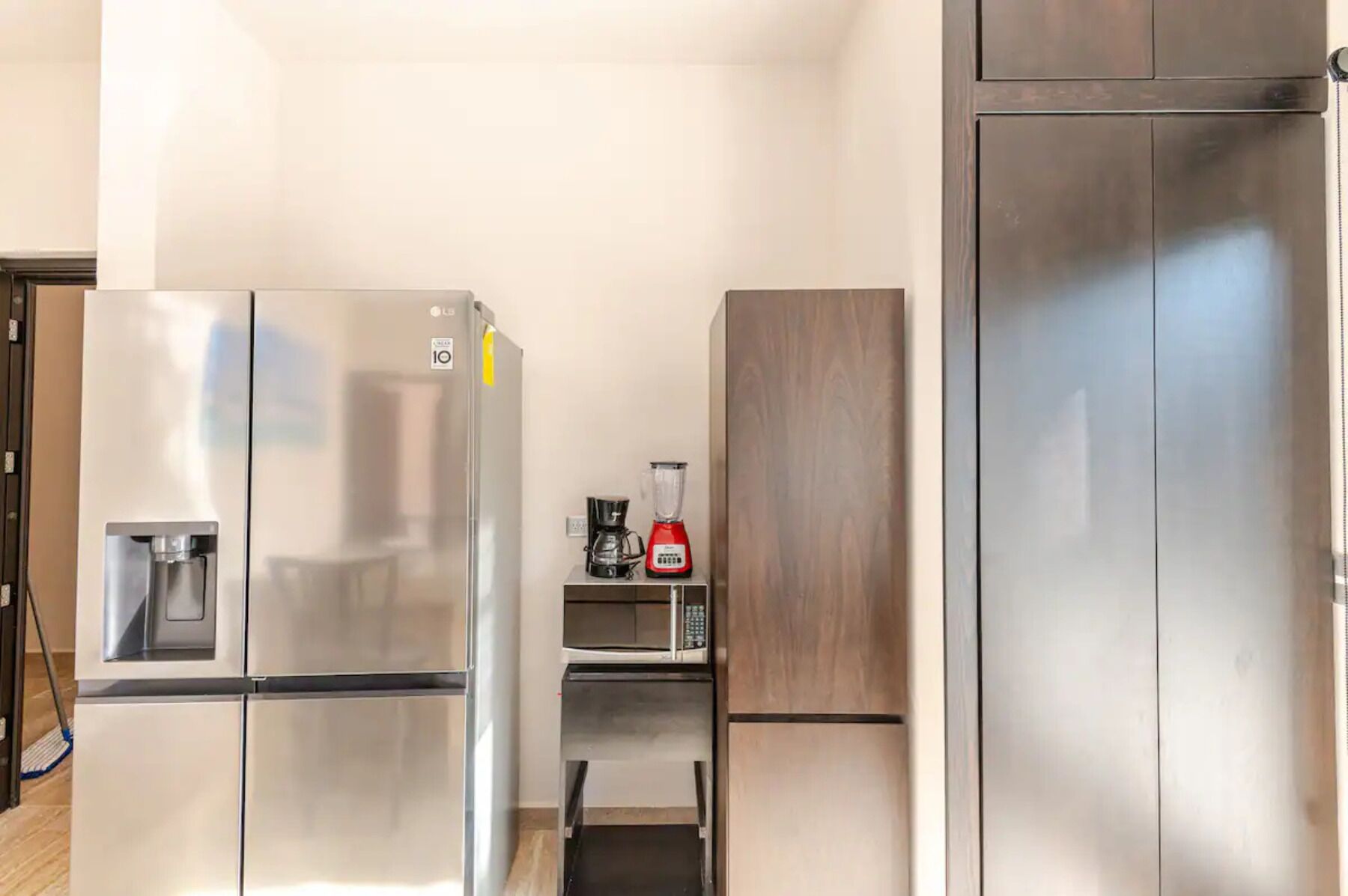 Una cocina compacta con un refrigerador de acero inoxidable, cafetera y microondas.