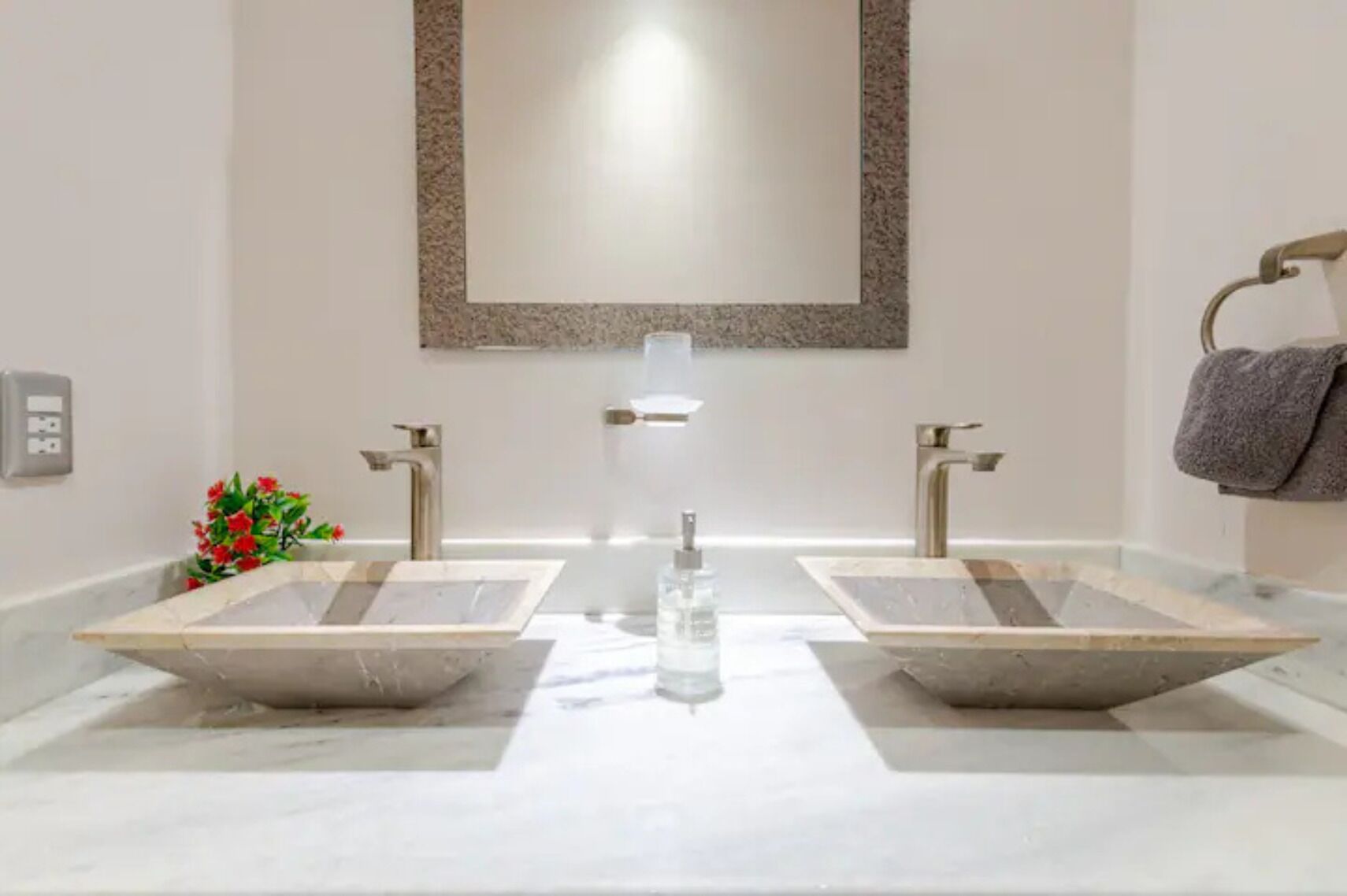 A bathroom with two sinks, a mirror, and a towel rack.