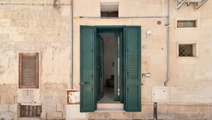 A building with a stone facade, a green door, and a small window with a number 21 sign. - San Giusto 21 Old Town - Lecce Selection (Lecce)