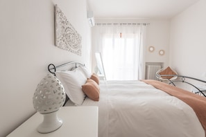 A bedroom with a bed, a bedside table with a lamp, a chair, and a radiator.