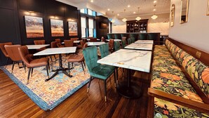 A restaurant with a long dining table, multiple chairs, and a sofa.