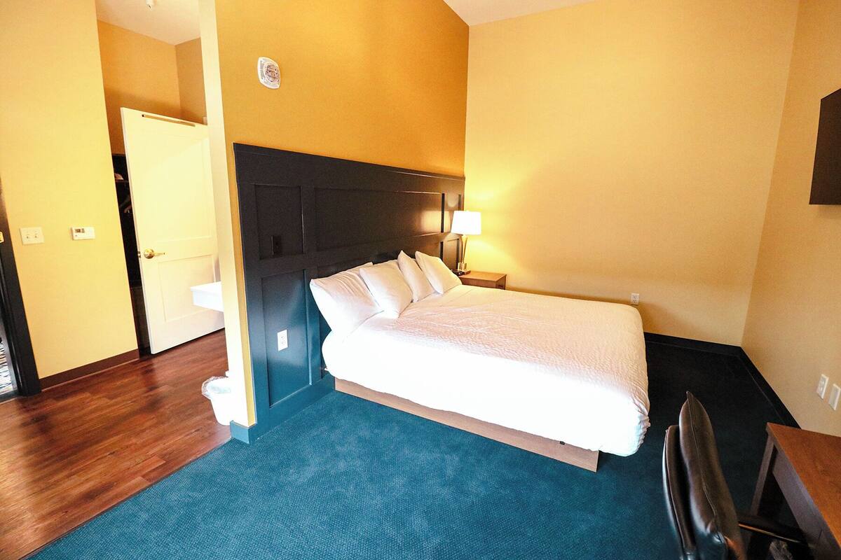 A hotel room with a bed, a desk, and a chair.