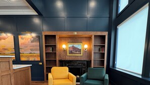 A cozy living room with green and yellow sofas, a fireplace, and a bookshelf.