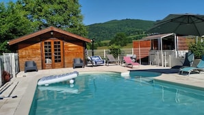A swimming pool with lounge chairs and a wooden cabin.