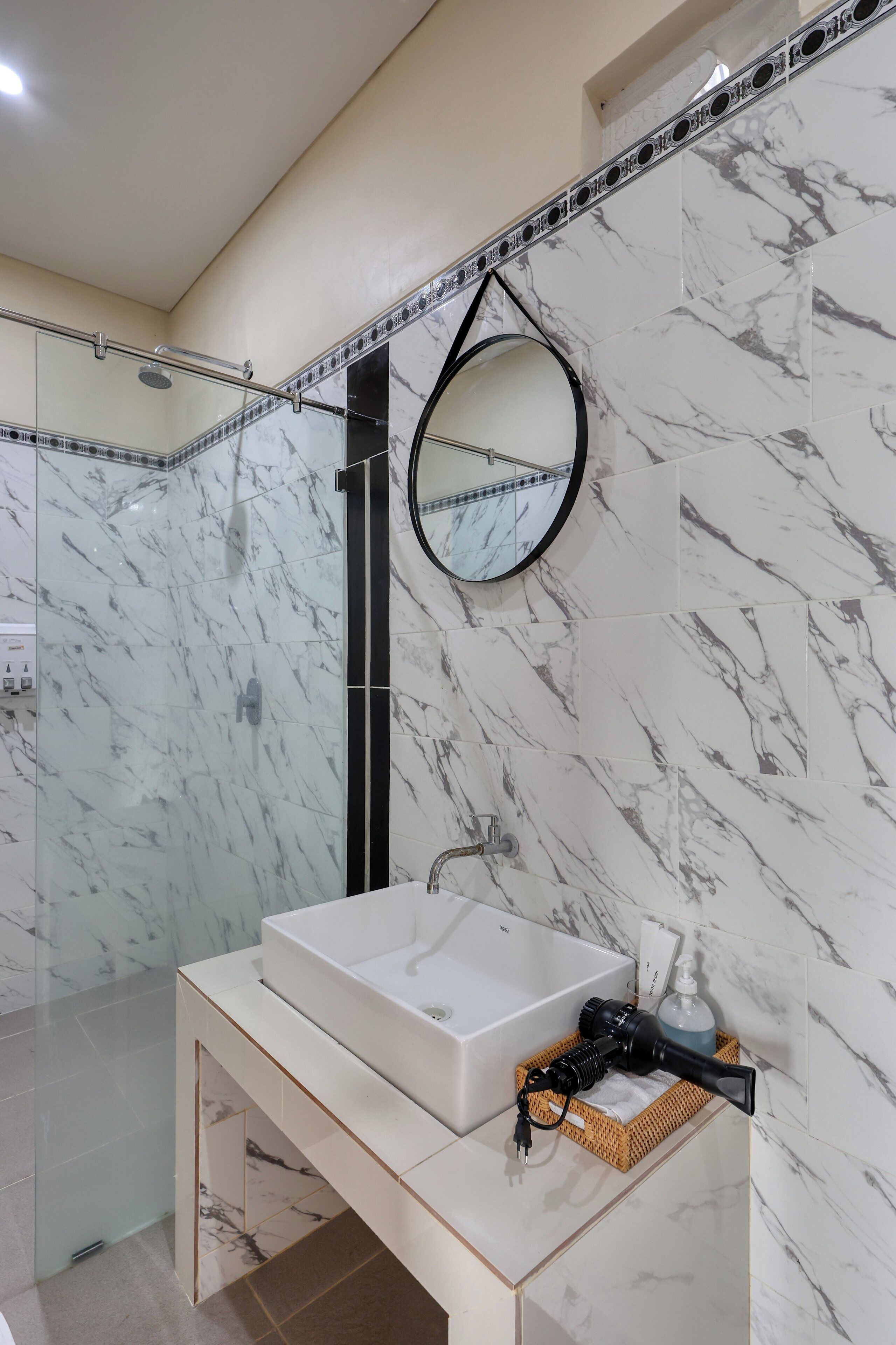 Un baño moderno con un lavamanos blanco, un espejo y un secador de pelo de mano en el mueble de tocador.