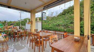 Een restaurant met houten tafels en stoelen, uitzicht op groen en een bord.