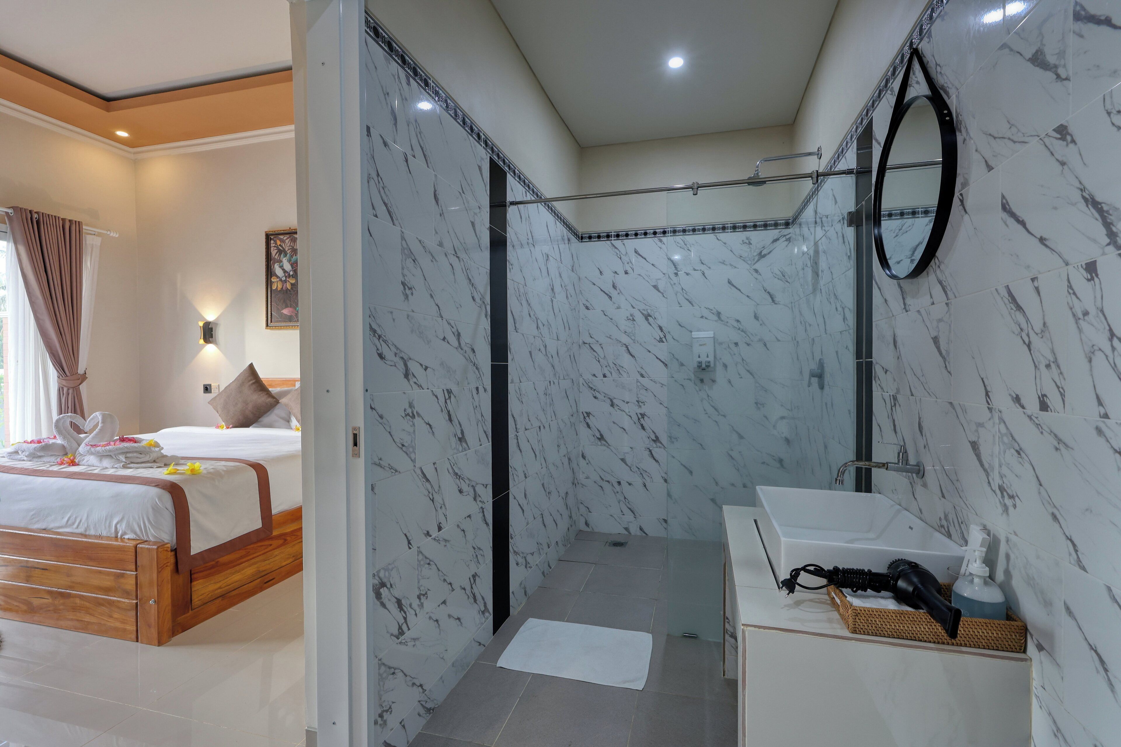 A hotel room with a bed, a bathroom with a shower, and a sink.
