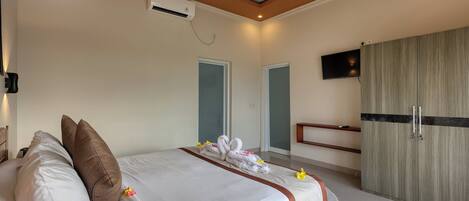 Una habitación de hotel con una cama, almohadas, un televisor y un armario.