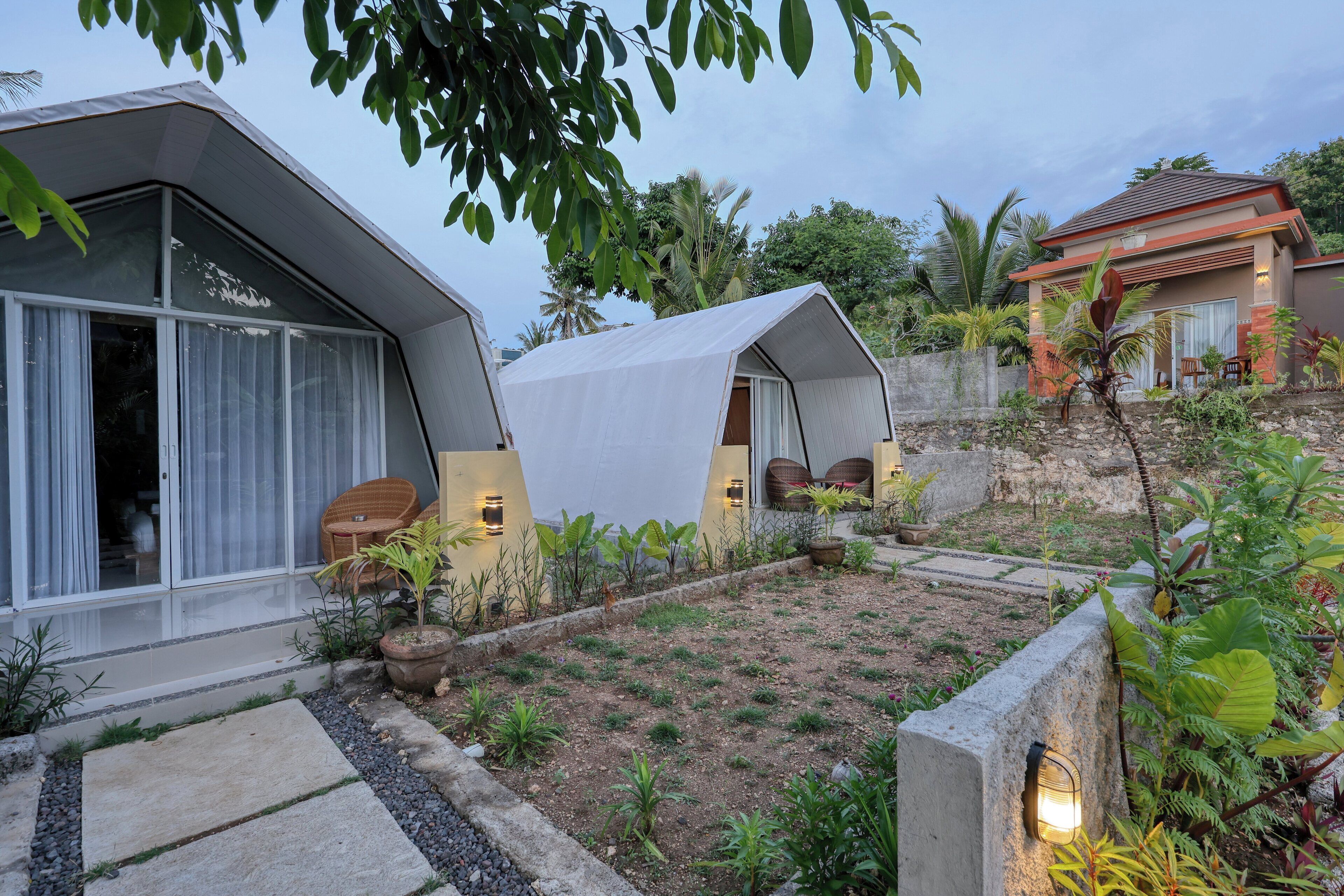 A modern house with a garden, a covered outdoor seating area, and a small patio.