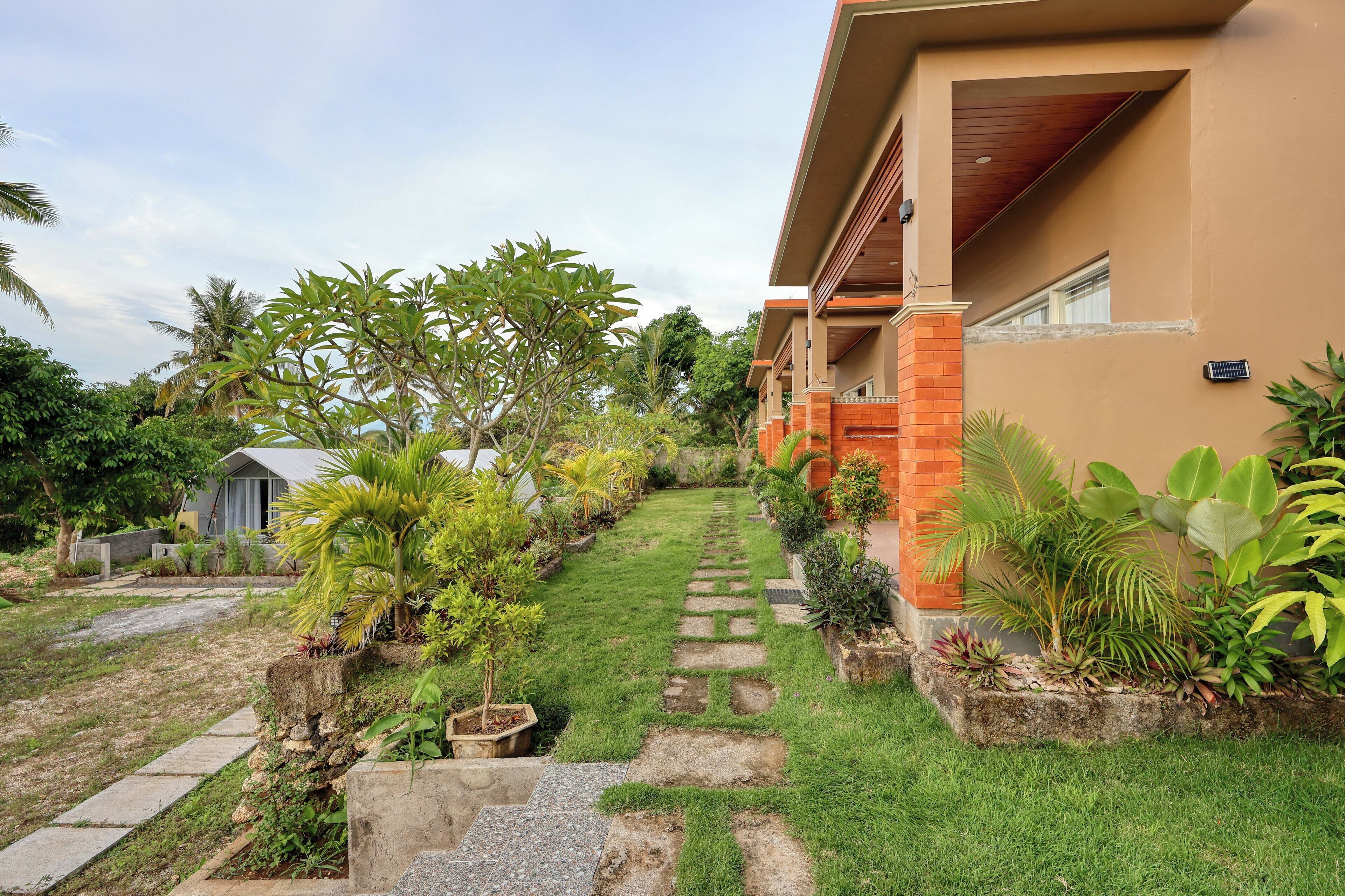 A well-maintained garden with a stone pathway leading to a building with a brown facade and a red brick base.