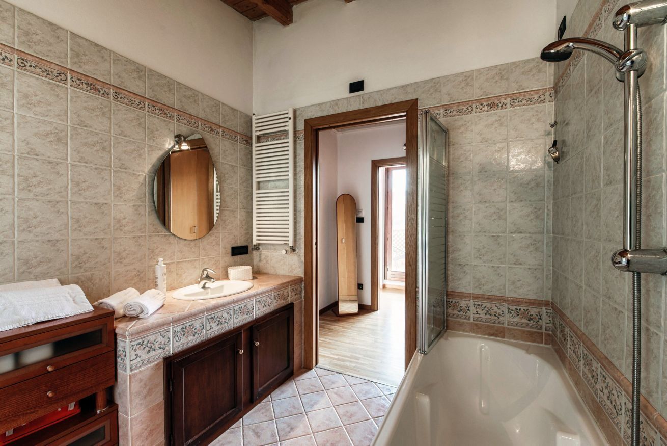 A bathroom with a bathtub, a sink, a mirror, and a wooden vanity.