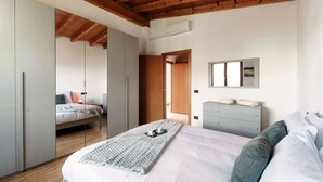 Un dormitorio con cama, cómoda, espejo y armario.