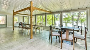 En rummelig stue med højt til loftet, store vinduer og synlige træbjælker.
